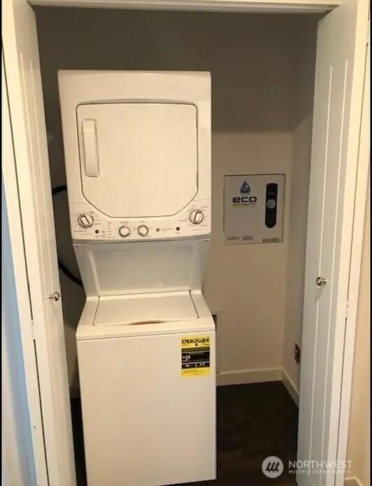 washroom featuring baseboards, laundry area, and stacked washer / dryer