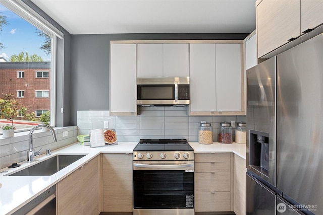 kitchen featuring a sink, light countertops, stainless steel appliances, decorative backsplash, and modern cabinets