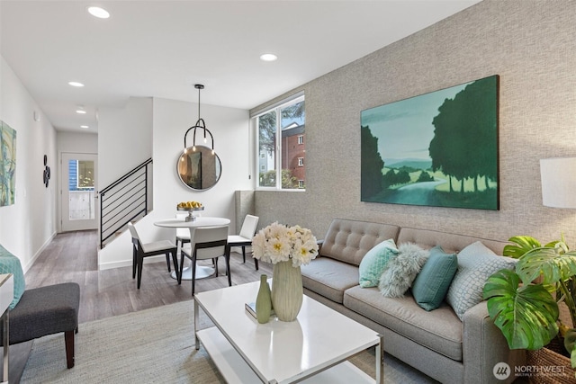 living room with an accent wall, stairs, recessed lighting, baseboards, and wood finished floors