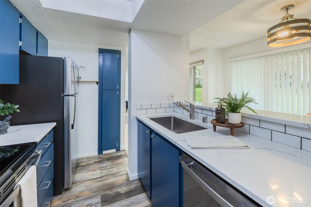 12621 NE 130th Way # D106, Kirkland, WA 98034 - kitchen with a textured ceiling, blue cabinetry, a sink, and wood finished floors
