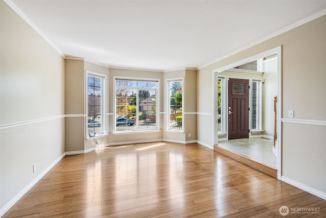spare room featuring crown molding, wood finished floors, and baseboards