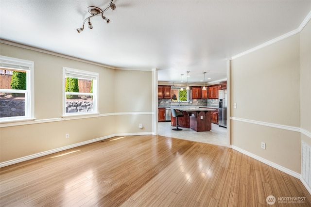 unfurnished living room with baseboards, light wood-type flooring, and crown molding
