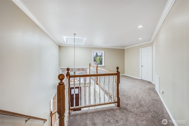 hall with an upstairs landing, carpet flooring, a skylight, ornamental molding, and baseboards