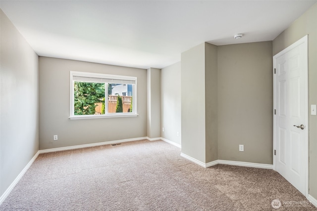 carpeted spare room featuring a smoke detector and baseboards