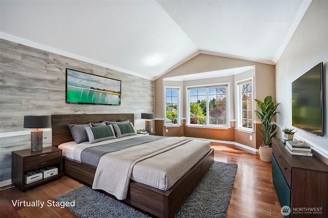 bedroom featuring an accent wall, multiple windows, lofted ceiling, wood finished floors, and crown molding