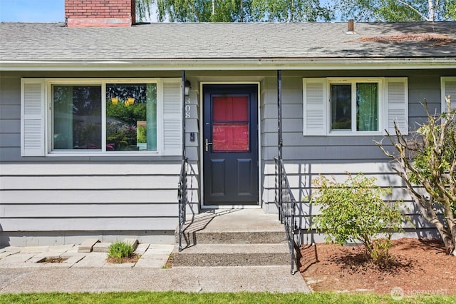 property entrance featuring a shingled roof and a chimney