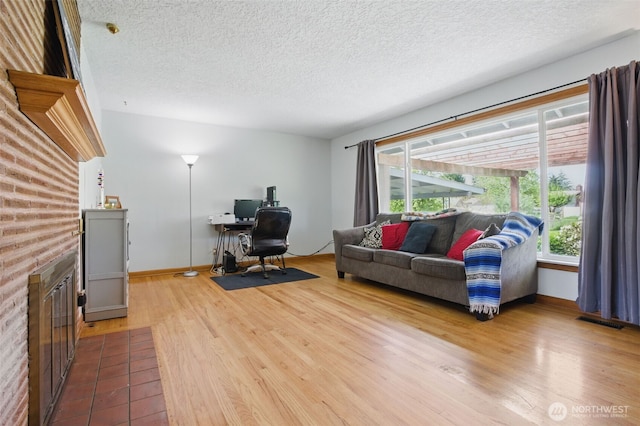 living area with a textured ceiling, visible vents, a healthy amount of sunlight, and wood finished floors