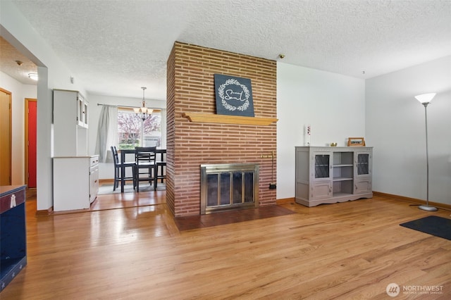 living room featuring wood finished floors, baseboards, a textured ceiling, and a notable chandelier