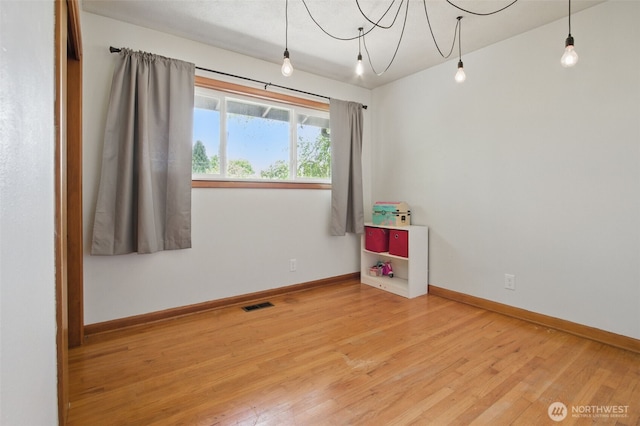 empty room with visible vents, baseboards, and wood finished floors