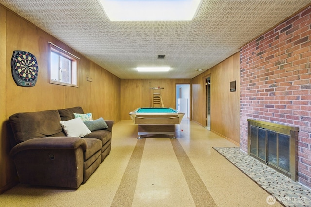 recreation room featuring a brick fireplace, pool table, wood walls, and visible vents