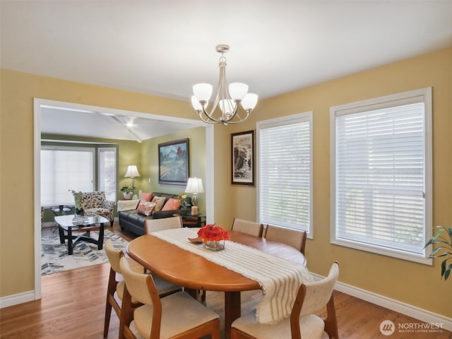dining space featuring baseboards, an inviting chandelier, and light wood-type flooring