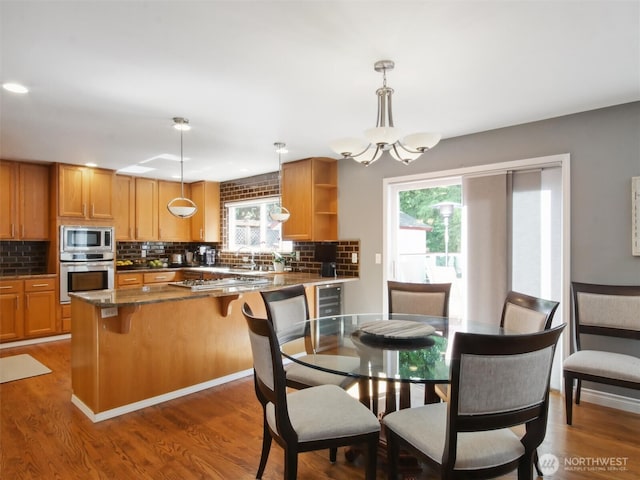 dining room featuring an inviting chandelier, beverage cooler, plenty of natural light, and wood finished floors