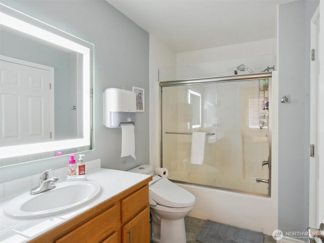 bathroom featuring vanity, enclosed tub / shower combo, and toilet