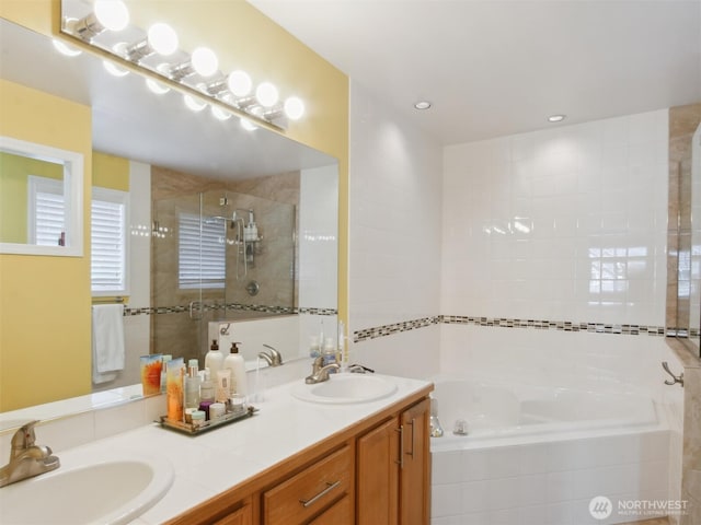 bathroom featuring a sink, double vanity, a stall shower, and a garden tub