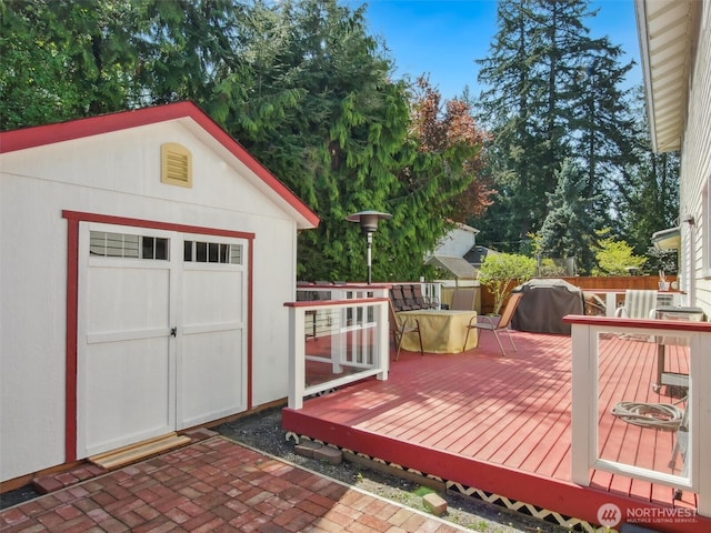 wooden terrace featuring an outdoor structure and a grill