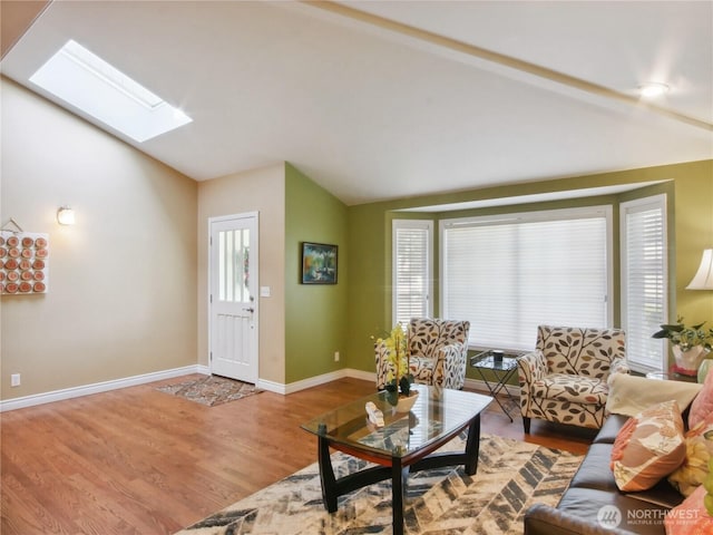 living area with baseboards, lofted ceiling with skylight, and wood finished floors