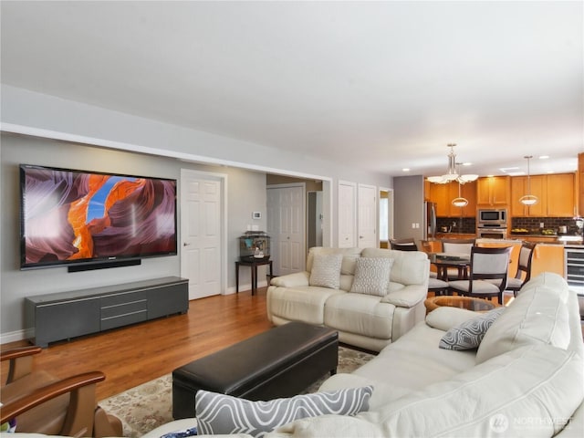 living room with baseboards, recessed lighting, wood finished floors, and a chandelier