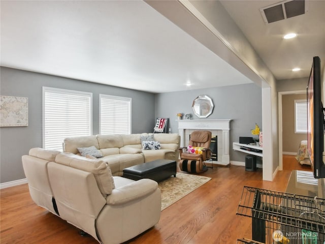 living area featuring visible vents, a tiled fireplace, wood finished floors, baseboards, and recessed lighting