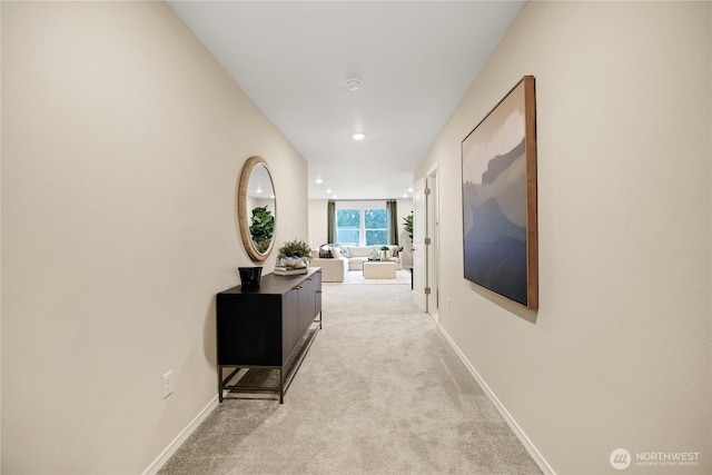 corridor featuring baseboards and light carpet