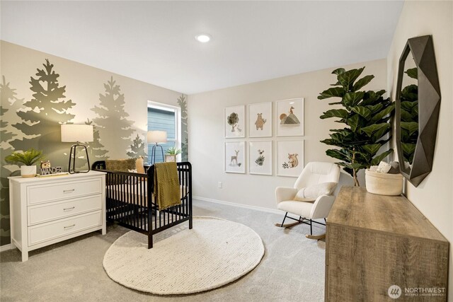 bedroom with a nursery area, baseboards, and light carpet