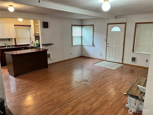 entrance foyer featuring baseboards, heating unit, wood finished floors, and beam ceiling