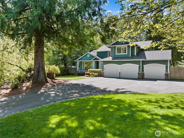tri-level home with a front yard, a garage, fence, aphalt driveway, and stone siding
