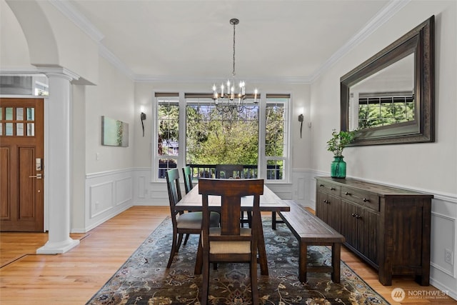 dining room featuring a chandelier, decorative columns, and light wood-style floors