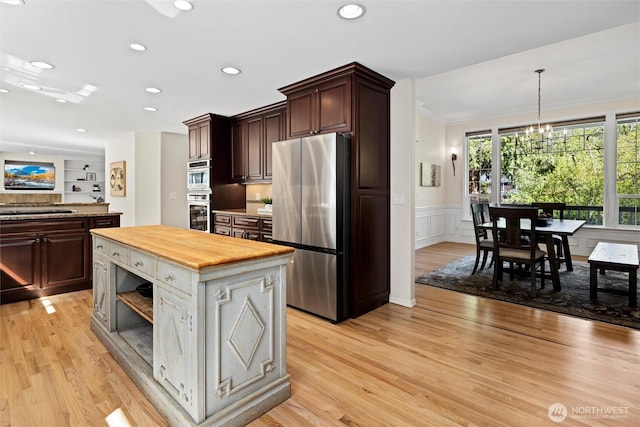 kitchen featuring wooden counters, light wood-type flooring, dark brown cabinets, freestanding refrigerator, and a notable chandelier