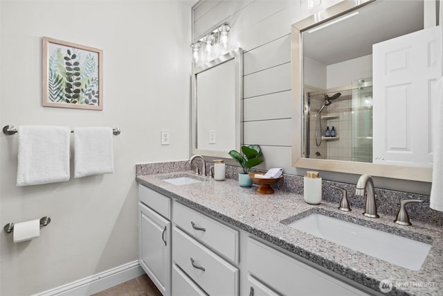full bathroom with double vanity, a sink, and a stall shower