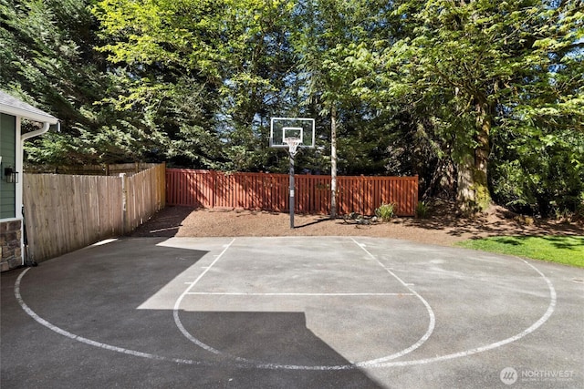 view of basketball court with fence and basketball hoop