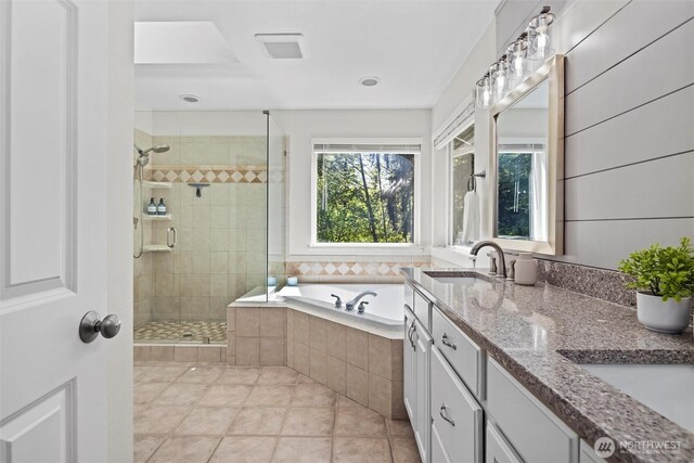 full bathroom featuring a garden tub, double vanity, tile patterned floors, a sink, and a stall shower