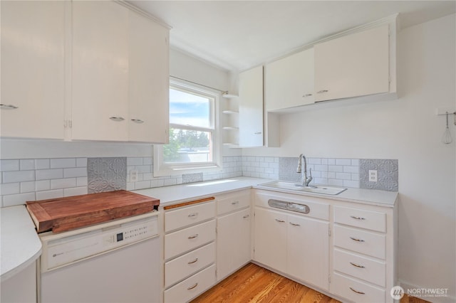 kitchen with dishwasher, a sink, light countertops, and decorative backsplash