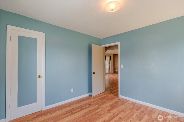 empty room with light wood-style flooring and baseboards
