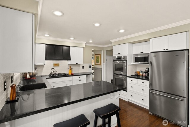 kitchen with ornamental molding, stainless steel appliances, a peninsula, and tasteful backsplash