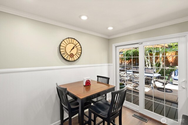 dining room with crown molding, visible vents, wood finished floors, and a wainscoted wall