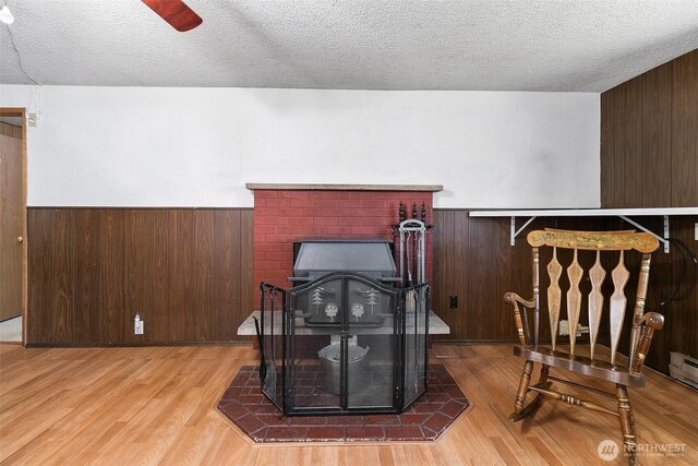 interior space featuring a textured ceiling, wood walls, wood finished floors, and a wainscoted wall