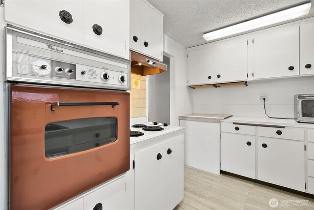kitchen with light countertops, white electric cooktop, white cabinetry, and oven