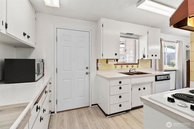 kitchen featuring white cabinets, a sink, white appliances, light countertops, and light wood-type flooring