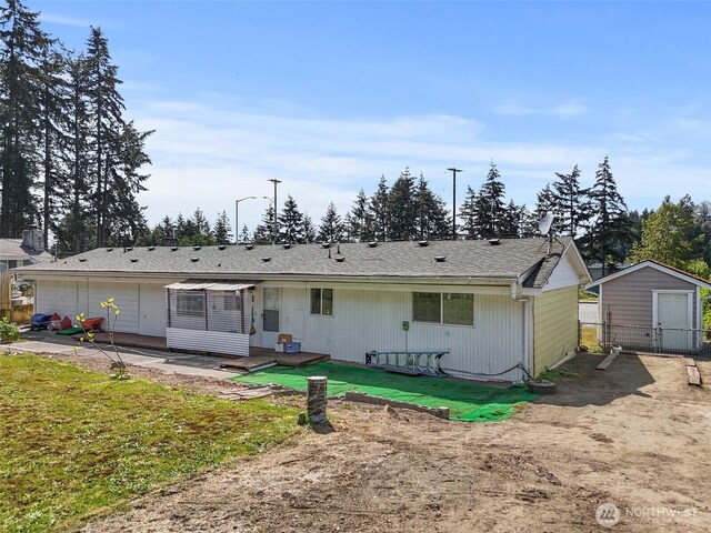 back of house with fence, an outbuilding, and a storage unit