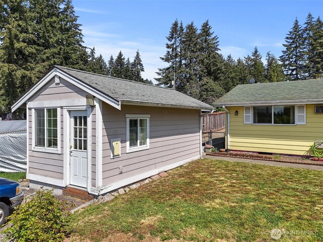 view of side of property featuring a yard, fence, and an outbuilding