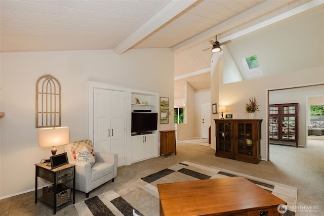 living room with light carpet, beamed ceiling, ceiling fan, high vaulted ceiling, and a skylight