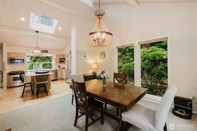dining room with an inviting chandelier, a skylight, light wood-style flooring, recessed lighting, and beamed ceiling
