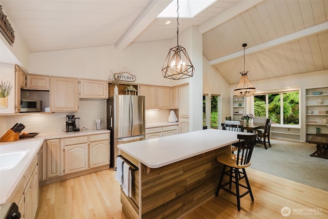 kitchen featuring light countertops, freestanding refrigerator, light brown cabinets, and tasteful backsplash
