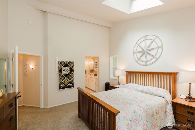carpeted bedroom with baseboards, high vaulted ceiling, ensuite bath, and a skylight