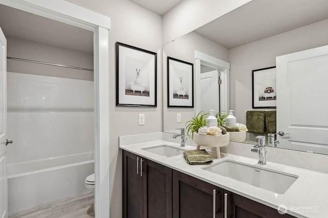 full bathroom featuring a sink, toilet, double vanity, and wood finished floors