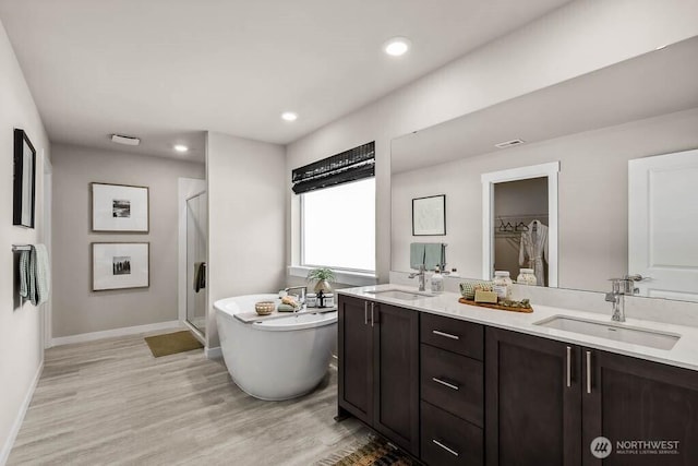 full bathroom with a sink, a shower stall, wood finished floors, and a freestanding bath
