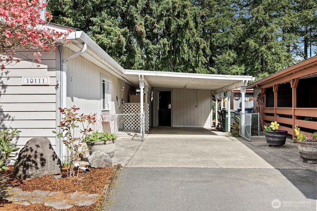 exterior space featuring an attached carport, fence, and aphalt driveway