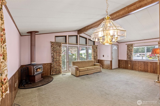 unfurnished living room featuring wooden walls, wainscoting, carpet floors, a chandelier, and vaulted ceiling with beams