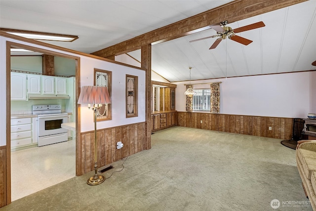 unfurnished living room featuring vaulted ceiling with beams, a ceiling fan, wainscoting, and wood walls
