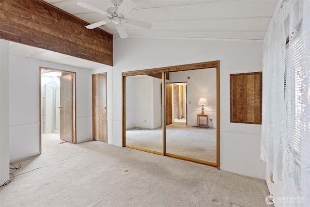 unfurnished bedroom featuring a closet, vaulted ceiling with beams, a ceiling fan, and carpet flooring